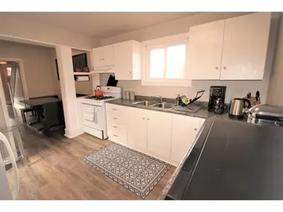 a kitchen with white cabinets and a black counter top at Doucet Guesthouse in Hamilton
