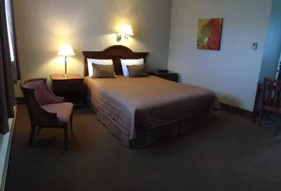 a hotel room with a bed and two chairs at Majers Motel in Stratford