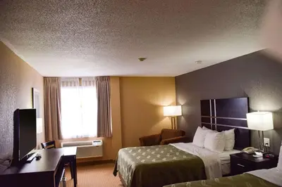 a hotel room with two beds and a desk and a window at Quality Inn in Bracebridge