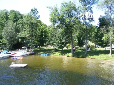a group of boats on a river with trees at Beachside on Lake Muskoka in Port Carling