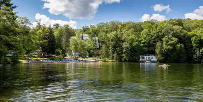 a body of water with trees and people in a boat at Sherwood Inn in Port Carling