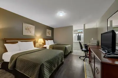 a hotel room with two beds and a flat screen tv at Knights Inn Burlington in Burlington