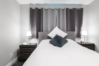 a bedroom with a large white bed with a pillow on it at ENTIRE 2 BEDROOM APARTMENT UPTOWN WATERLOO - e3 in Waterloo