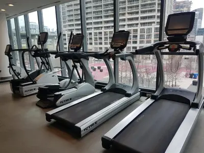 a row of treadmills in a gym with windows at Executive 1 Bedroom Condo sleeps 2 in Toronto