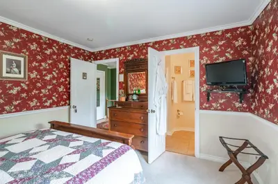a bedroom with a bed and a tv on the wall at Abacot Hall Bed & Breakfast in Niagara on the Lake