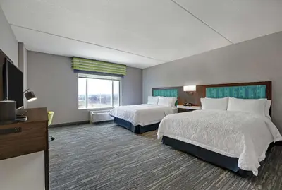 a hotel room with two beds and a flat screen tv at Hampton Inn Peterborough in Peterborough
