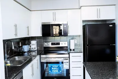 a kitchen with white cabinets and black appliances at Luxury 2 bedroom Condo With Parking and Swimming Pool Near Square One in Mississauga