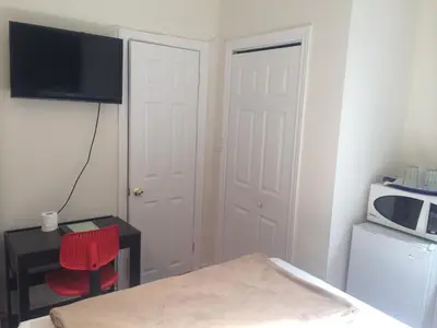 a small room with a red chair and a table and a microwave at Keppner Guesthouse in Toronto