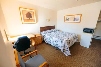 a hotel room with a bed and a desk and a chair at Clarkson Village Motel, 1815 Lakeshore Rd West Mississauga in Mississauga