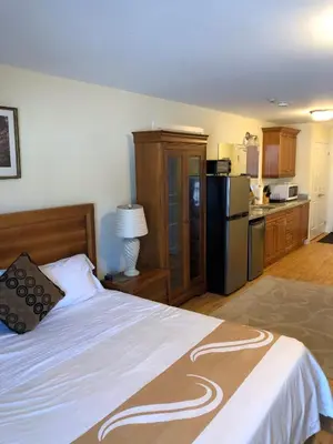 a bedroom with a large bed and a kitchen at Muskoka Lakes Hotel and Resorts in Port Carling