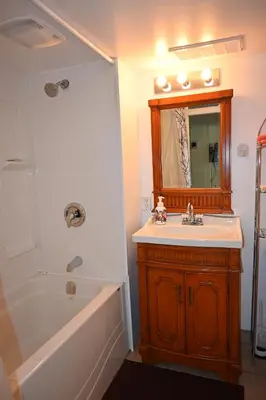 a bathroom with a tub and a sink and a mirror at Oasis Suite in Niagara Falls