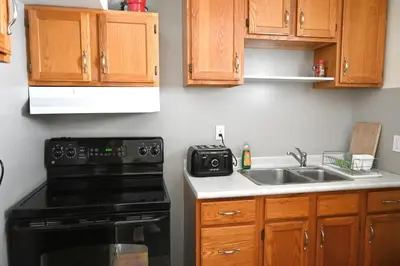 a kitchen with wooden cabinets and a stove and a sink at Oasis Suite in Niagara Falls