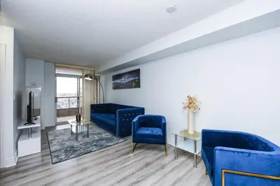 a living room with two blue chairs and a tv at PlanURstay - Luxury 1BR Condo with City View in Mississauga
