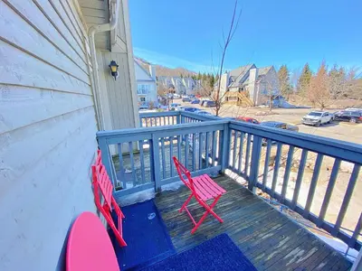 two red chairs sitting on a deck on a house at Gorgeous Loft in the Heart of Blue Mountain in Blue Mountains
