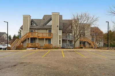 a large house with a deck in a parking lot at Condo 206 at North Creek Resort in Blue Mountains