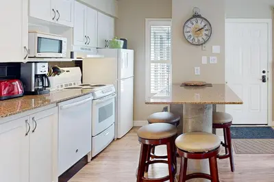 a kitchen with white cabinets and a counter with stools at Condo 413 at North Creek Resort by Vacasa in Blue Mountains