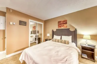 a bedroom with a large white bed and a mirror at Condo 903 at North Creek Resort in Blue Mountains