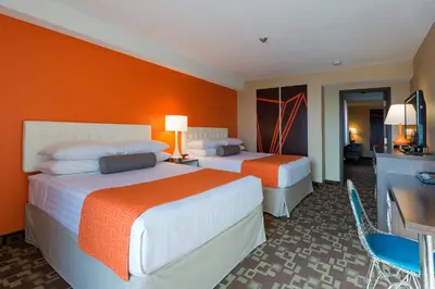 two beds in a hotel room with orange walls at Howard Johnson Plaza by Wyndham by the Falls Niagara Falls in Niagara Falls