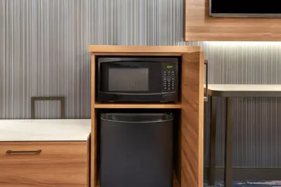a microwave in a wooden cabinet with a trash can at Fairfield by Marriott Niagara Falls, Canada in Niagara Falls