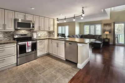 a kitchen with white cabinets and a living room at Large luxurious upper floor condo in Sierra Lane in Blue Mountains