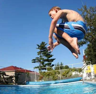 a young man jumping into a swimming pool at Saga Resort in Wasaga Beach