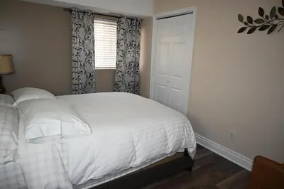 a bedroom with a white bed and a window at Elgin Suite in Niagara Falls