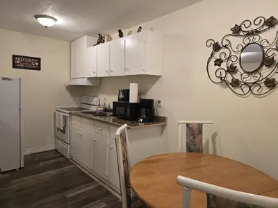 a kitchen with white cabinets and a wooden table at Capitol Suite in Niagara Falls