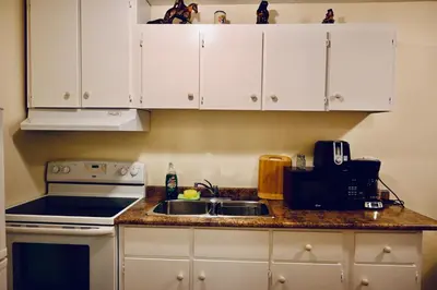 a kitchen with white cabinets and a sink and a stove at Capitol Suite in Niagara Falls