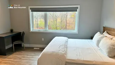 a bedroom with a bed and a desk and a window at Orchard Run Chalet in Blue Mountains