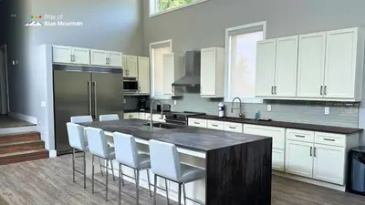 a kitchen with white cabinets and a black counter top at Orchard Run Chalet in Blue Mountains
