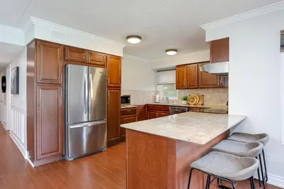 a kitchen with wooden cabinets and a stainless steel refrigerator at Blue Mountain, 3 BR - 108 Mountain Walk Chalet in Blue Mountains