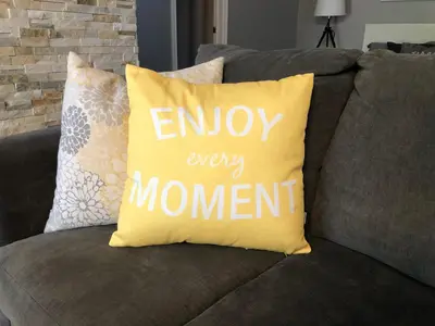 a pillow that says enjoy every moment on a couch at Blue Mountain Hideaway at North Creek Resort in Blue Mountains