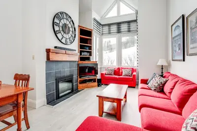 a living room with a red couch and a fireplace at 2 Bdrm Ski In Ski Out Loft at Blue Mountain in Blue Mountains