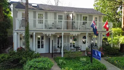 a white house with two flags in front of it at Harrogate House Inn in Niagara on the Lake