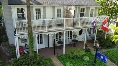 a house with a white deck and a balcony at Harrogate House Inn in Niagara on the Lake
