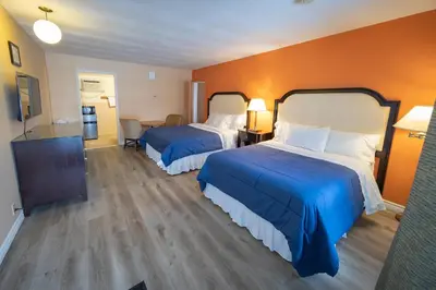 two beds in a hotel room with orange walls at Choice Inn by the falls in Niagara Falls
