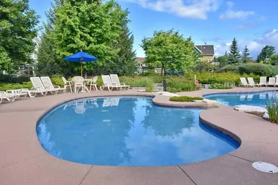 a pool with chairs and tables and an umbrella at Executive Town Home-Mountain View-Historic Snowbridge Village, Walking Distance to the Resort in Collingwood