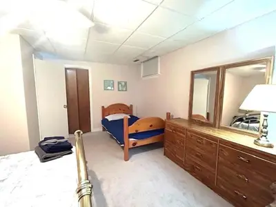 a room with a bedroom with a bed and a mirror at Leslie in Wasaga Beach