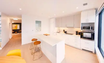 a kitchen with white cabinets and a counter and stools at The Laundry Rooms - Waterloo in Waterloo