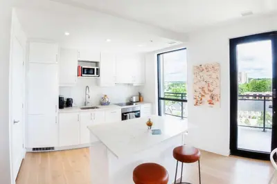 a kitchen with white cabinets and a large window at The Laundry Rooms - Waterloo in Waterloo
