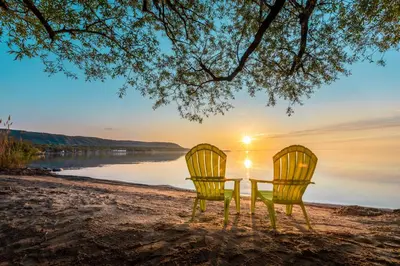 two yellow chairs sitting on a beach with the sunset at Boutique Suite #3 in Blue Mountains