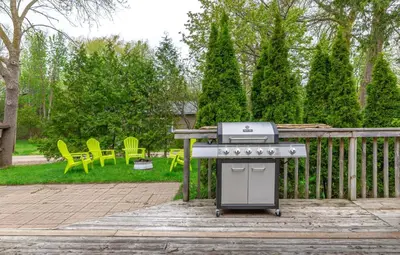 a grill on a patio with chairs and a yard at Boutique Suite #5 in Blue Mountains
