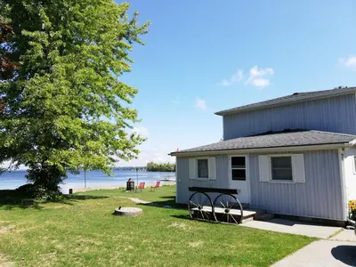 a house with a picnic table in front of a lake at Entire waterfront cottage in carrying place in Carrying Place
