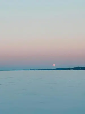 a sunset over the water with the moon in the sky at Entire waterfront cottage in carrying place in Carrying Place