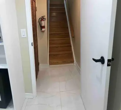 a hallway with a door leading to a room with a staircase at 3 Spacious Bedroom Basement Apartment in Richmond Hill in Richmond Hill