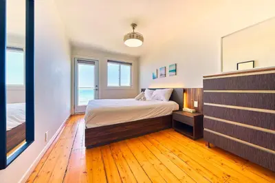 a bedroom with a bed and two windows at The Long Beach Resort - Beachfront Cottages & Townhouse Suites in Wainfleet