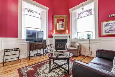 a living room with red walls and a fireplace at School House Bed and Breakfast C.1859 in Niagara on the Lake
