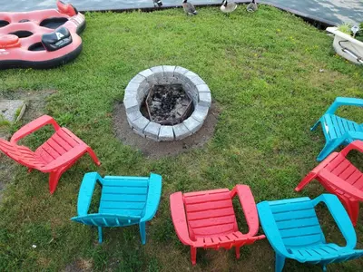 a group of colorful chairs and a fire pit at Cottage with River Front & minutes away from Beach in Wasaga Beach