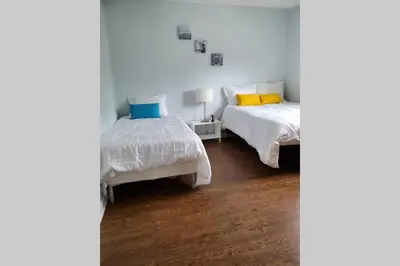 a white bedroom with two beds and a lamp at Cottage with River Front & minutes away from Beach in Wasaga Beach