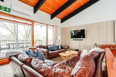 a living room with leather couches and a television at Blue Mtn Chalet with a Sauna, Sleeps 20 in Blue Mountains